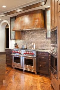 Leather Tabernash Range Hood over a stainless steel stove and dark wood cabinets