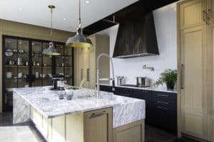 Tabernash custom metal range hood above a gas stove within a modern kitchen with wooden cabinets