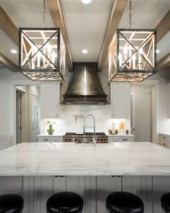 white kitchen with marble countertop and wolf range to accent the dark antique custom montrose range hood with polished chrome details