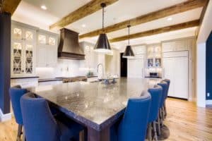Dark Wash Montrose Range Hood in a kitchen with blue chairs surrounding a table
