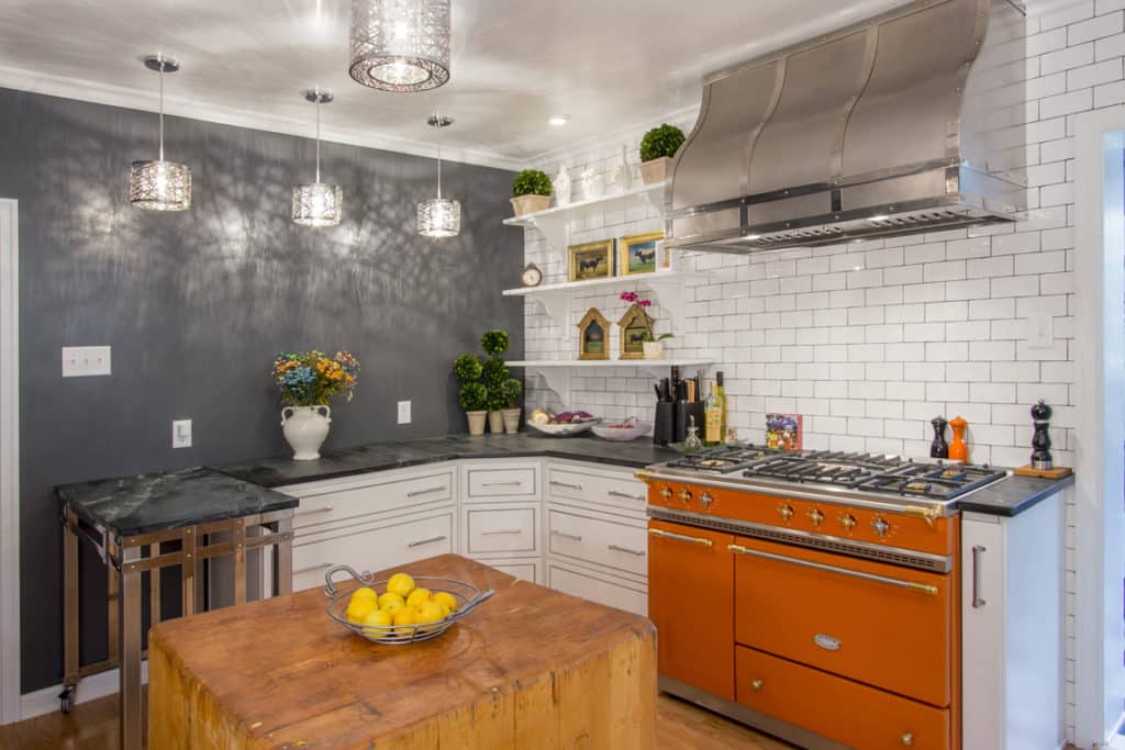 Burnished stainless contemporary hood with orange kitchen cabinets