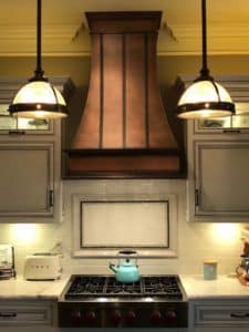 custom montrose metal range hood vent with antique copper patina finish in a modern kitchen