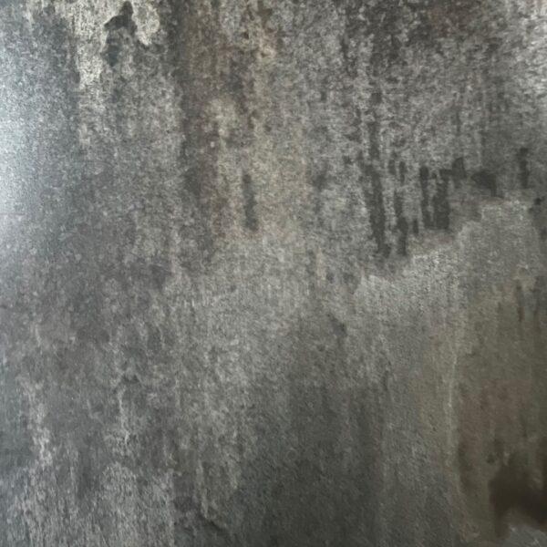A close-up of Rustic Reclaimed, featuring a textured, weathered concrete wall with varied gray tones, dark streaks, and rough, uneven surfaces.