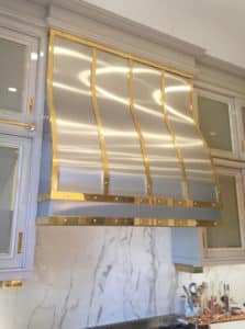 clean stainless kitchen vent hood cover with brass details