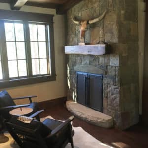 Antique fireplace made out of stone with two chairs sitting in front of it