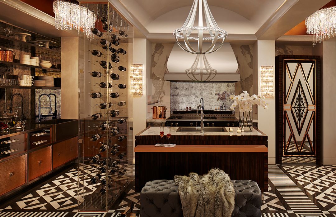 blog-dxv Experience a luxurious Art Deco kitchen with blog-dxv's central island featuring a wine rack for multiple bottles, decorative chandeliers, geometric tile flooring, and flowers on the counter.
