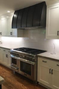custom metal vent hood shroud tight between cabinets in white kitchen