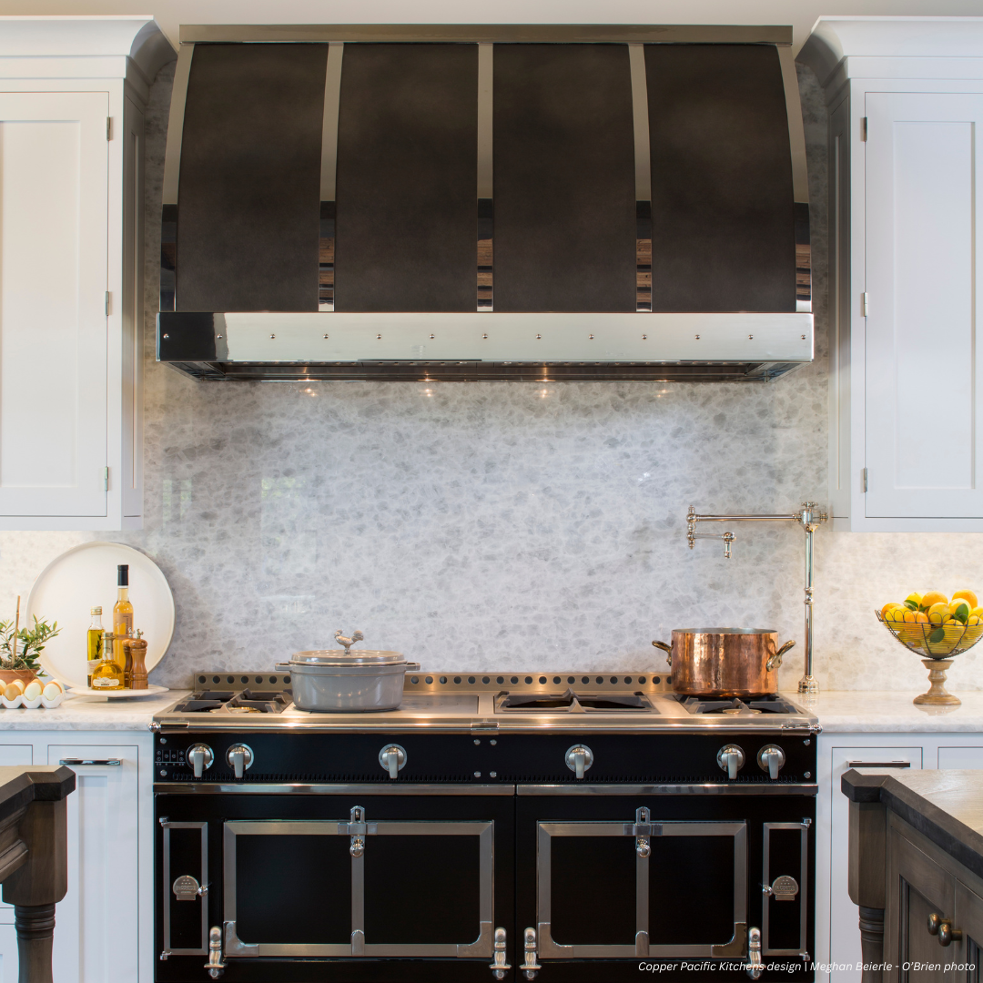 Aspen gallery1✅ (2) The Aspen gallery1✅ (2) showcases a modern kitchen featuring a black and stainless steel stove, matching range hood, marble backsplash, countertop with a pot, kitchen essentials, fruit bowl, and neatly arranged cooking utensils.