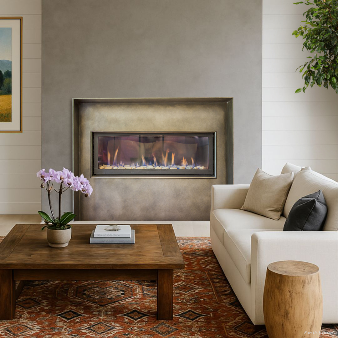 A modern living room featuring the Surround 4 gas fireplace in a gray wall, a white sofa with beige pillows, a wooden coffee table with a book and orchid, a patterned rug, and a green plant in the corner.