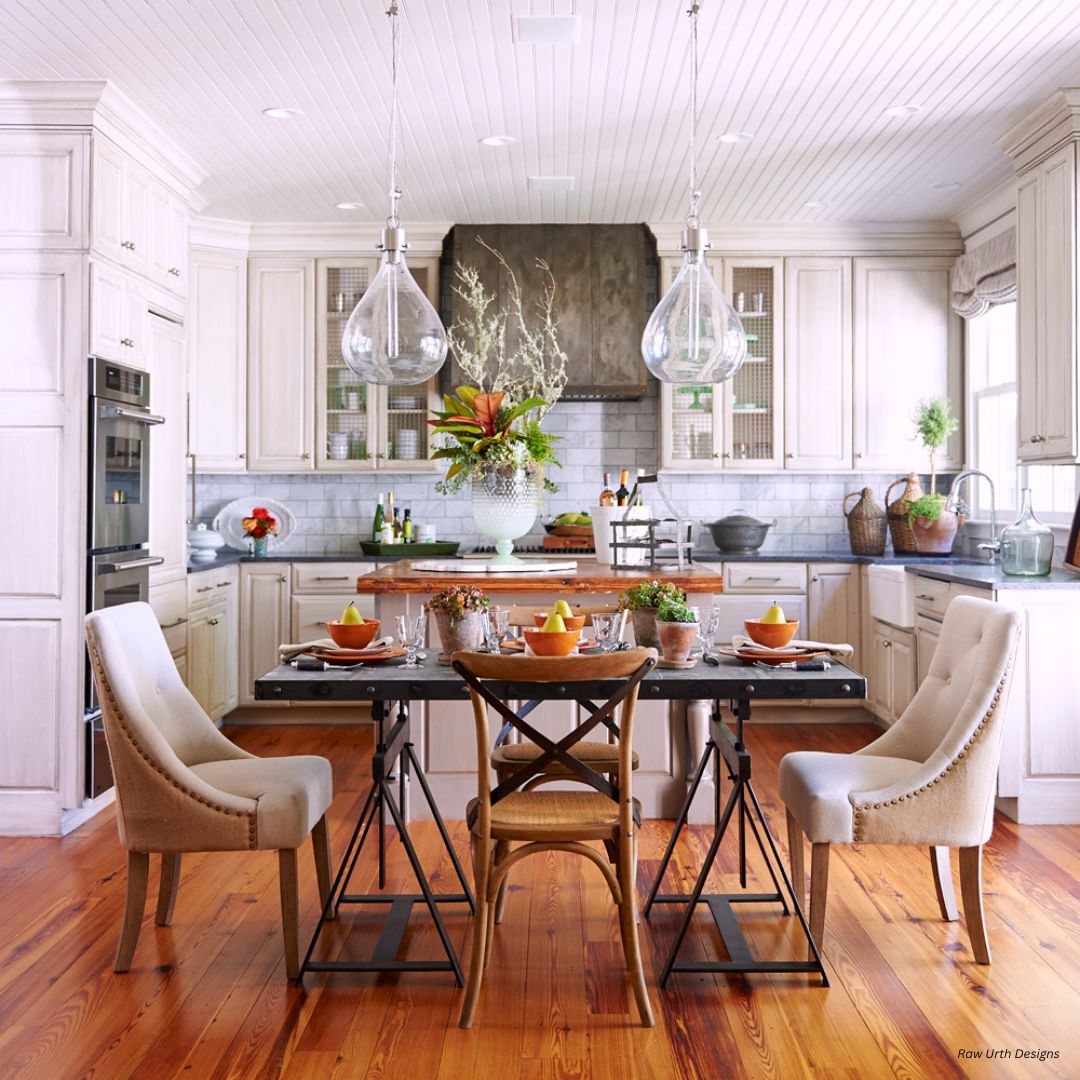 aspen-classic-gallery2 The aspen-classic-gallery2 features a cozy kitchen with white cabinets, a wooden island, and two large pendant lights. It showcases tables set with dishes and orange bowls. Potted plants, a cutting board, and jars adorn the counters, while light wooden flooring adds warmth.