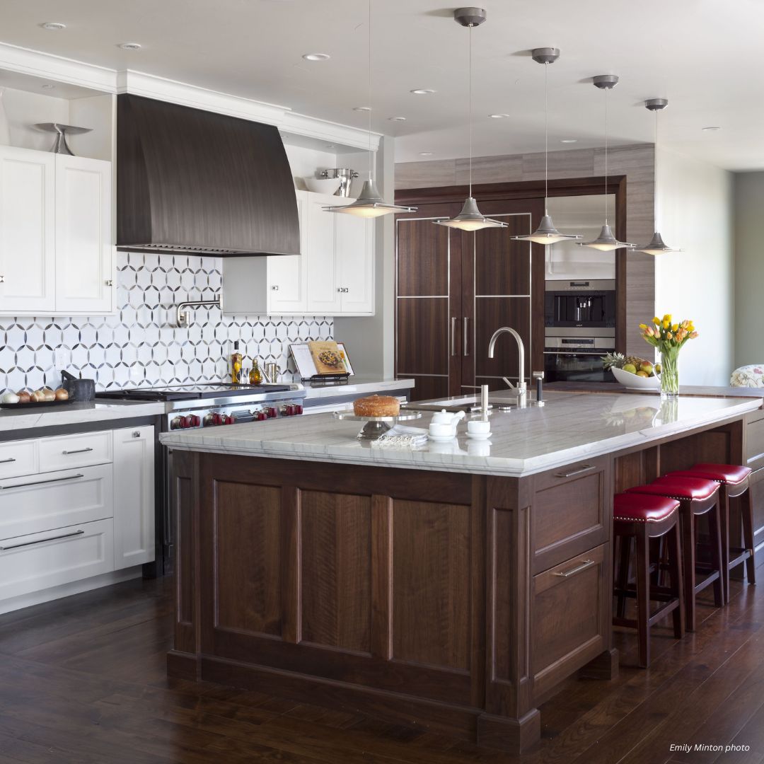 Modern kitchen featuring Aspen Essential - gallery 2√: white upper cabinets, dark wood lowers and island, stainless steel appliances, hexagon tile backsplash, pendant lights, red island stools, and a vase of yellow tulips on the counter.