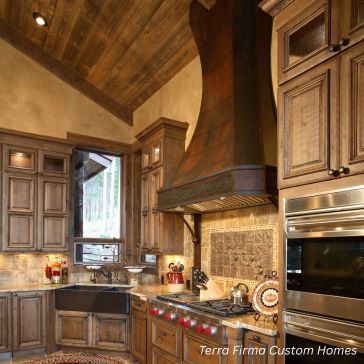 Patina 6 column photos-2 Rustic kitchen with wood cabinets, metal range hood, farmhouse sink, stainless steel appliances, stone backsplash, and sloped wood ceiling. "Patina 6 column photos-2" appears in the bottom right corner.