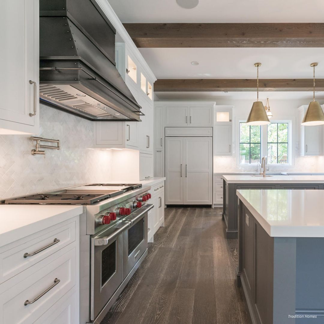 creed-classic-gallery1√ Modern kitchen featuring creed-classic-gallery1√ white cabinets, stainless steel appliances, large stove with red knobs, marble backsplash, gold pendant lights, island, wood beam ceiling accents, and wide plank dark wood flooring.