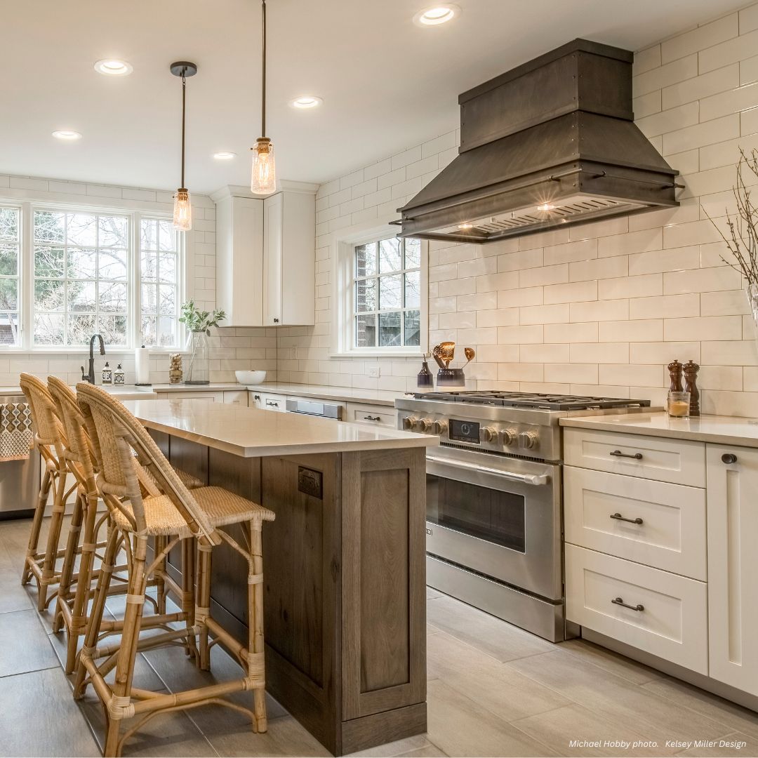 creede-classic-gallery3√ Modern kitchen featuring the creede-classic-gallery3√, a large island, two woven bar stools, stainless steel appliances, white subway tile backsplash, range hood, and bright light from two windows.