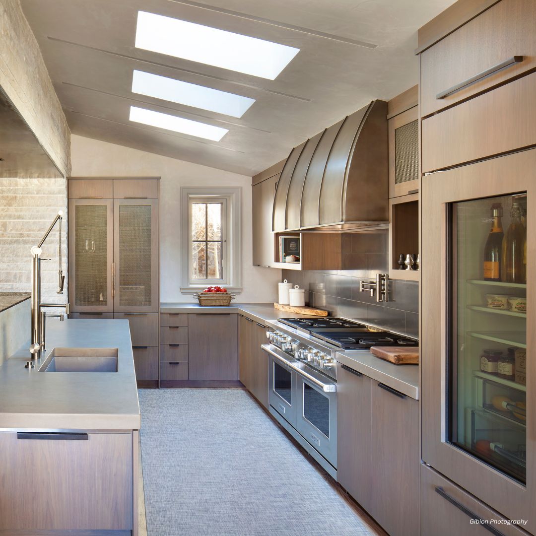 snowmass-classic-gallery3√ The snowmass-classic-gallery3√ features a modern galley layout with wood cabinetry, stainless steel appliances, a spacious wine fridge, skylights, plentiful counter space, and abundant natural light from skylights and an end window.