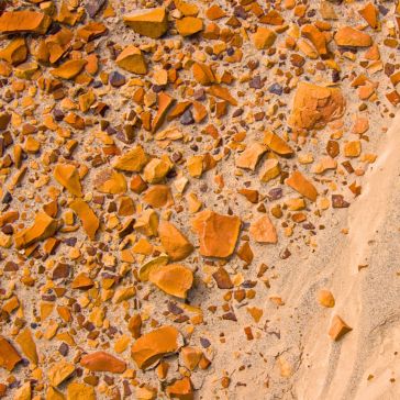 83 A close-up view of the product "83" shows scattered orange and brown rocks and pebbles on sandy ground, with a slight diagonal slope visible on the right side.