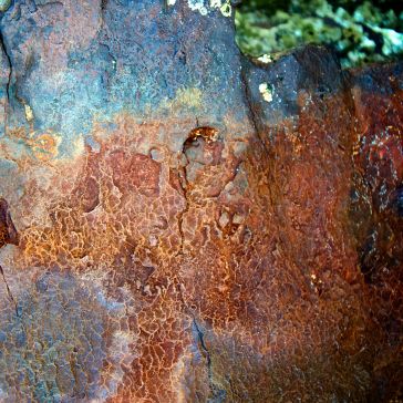 96 Close-up of the 96 surface, featuring rusty, textured metal in shades of orange, brown, blue, and green with cracks, rough patches, and weathered patterns.