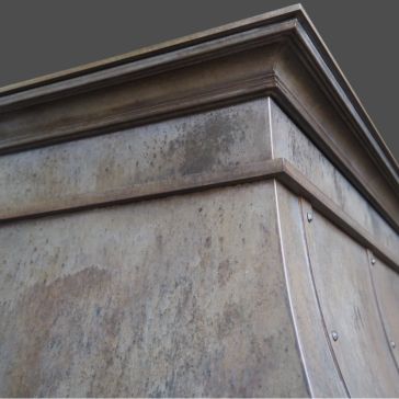 Close-up of the top corner of the Agate 6772 - 3 metal cabinet or vent hood, featuring a weathered, brushed finish with visible rivets against a plain gray background.