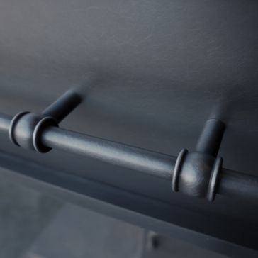 Close-up of the Antique 5 metal rod, featuring two cylindrical supports and ring-shaped accents, mounted on a smooth, dark surface.