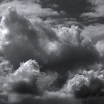 In the black and white image "Antique4," dark, dense clouds dominate the sky, creating a dramatic, moody atmosphere. Light breaks through in places, highlighting intricate cloud textures.