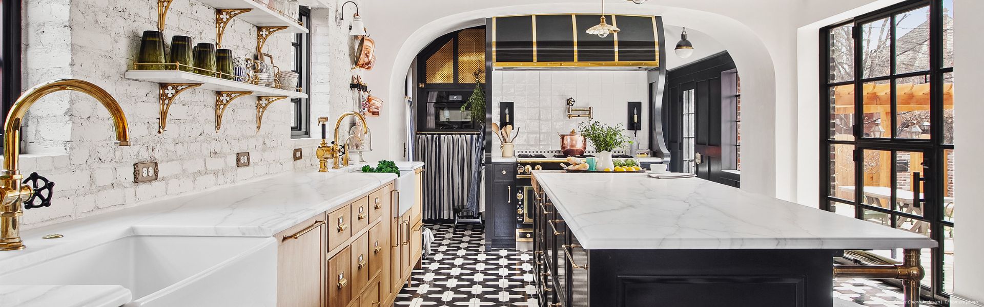 Banner Aspen Custom ✅ The Banner Aspen Custom kitchen features marble countertops, gold fixtures, black-and-white patterned tile flooring, open shelving for dishes, a farmhouse sink, and large windows for natural light.