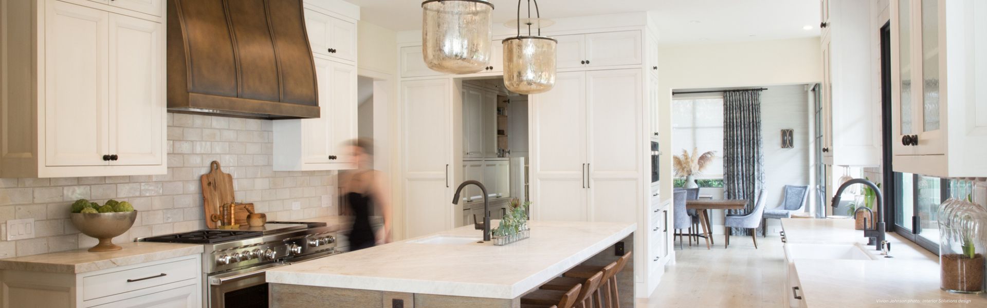 Banner Masonville Custom ✅-2 The Banner Masonville Custom ✅-2 features a bright, modern kitchen with white cabinets, a spacious island, pendant lights, stainless steel appliances, and dining area with windows in the background.