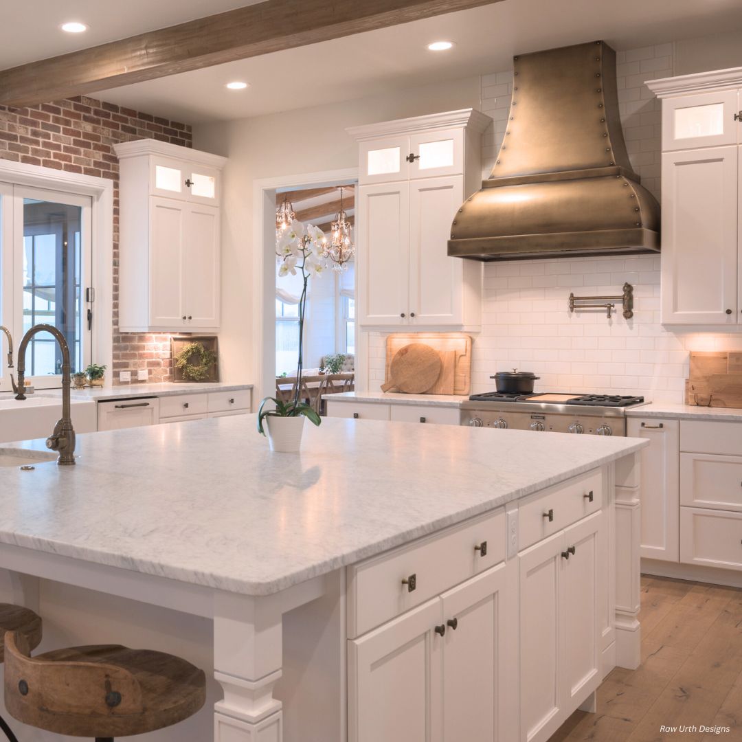 The Bonner Peak gallery2✅ features an elegant kitchen with white cabinets, a marble island, wooden accents, brick wall details, a brass range hood, built-in stove, and under-cabinet lighting for a bright, inviting space.