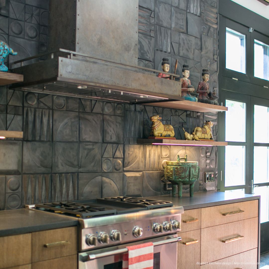 Modern kitchen featuring Boulder gallery2✅ stainless steel stove, wooden cabinets, and open shelves with Asian-inspired decor against a geometric gray backsplash. Tall windows fill the space with natural light.