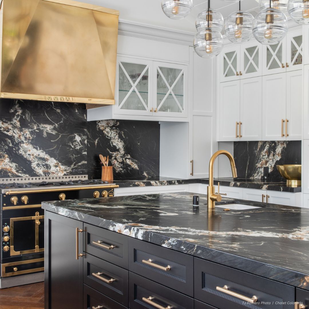 Box gallery3✅ Modern kitchen featuring Box gallery3✅: black marble countertops and backsplash, gold-accented stove, hood, faucet, cabinet handles, globe pendant lights, and white upper cabinets with glass doors.