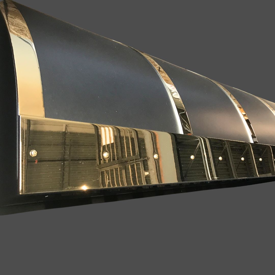 Brass Polished 2 Angled close-up of the Brass Polished 2 vent with a metallic and black reflective surface, capturing ceiling lights and beams in its shine against a plain dark background.