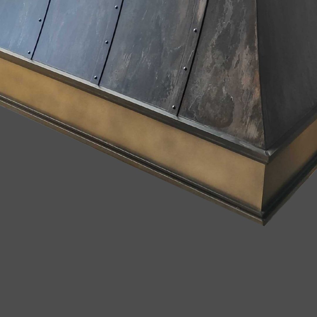 Close-up of the Bronze Cast 1, showing its sloped, riveted dark panels and flat brushed gold-colored trim at the base, set against a plain gray background.