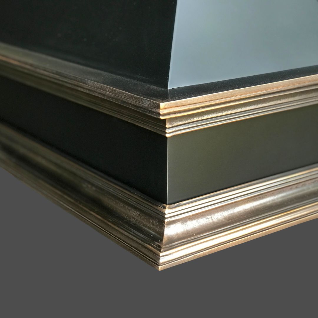Close-up view of an architectural corner featuring Bronze Cast 2 panels with metallic trim and layered molding, showcasing sharp lines and a modern, elegant design.