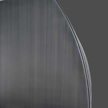 Brushed 1 Close-up of the curved edges of three stacked Brushed 1 metal spoons against a plain gray background.