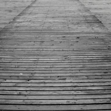 Brushed 6 Brushed 6 is a black and white photo of a wooden pier stretching over water, fading into the mist. The strong horizontal lines of the planks guide your gaze toward the distant horizon.