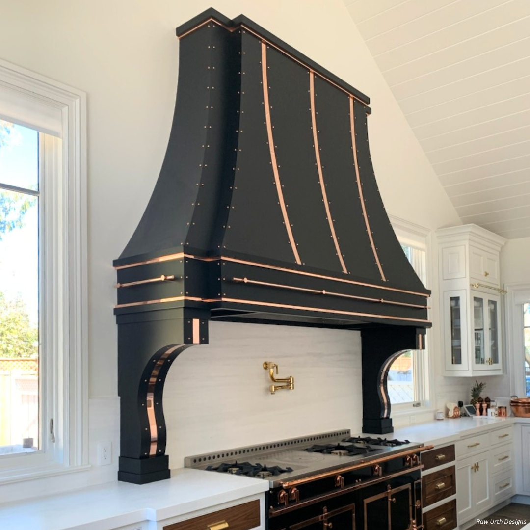 Cherry Hills gallery1 Cherry Hills gallery1 showcases a modern kitchen with a large black and copper range hood, white walls, gold faucet, and windows on both sides for a bright, stylish look.