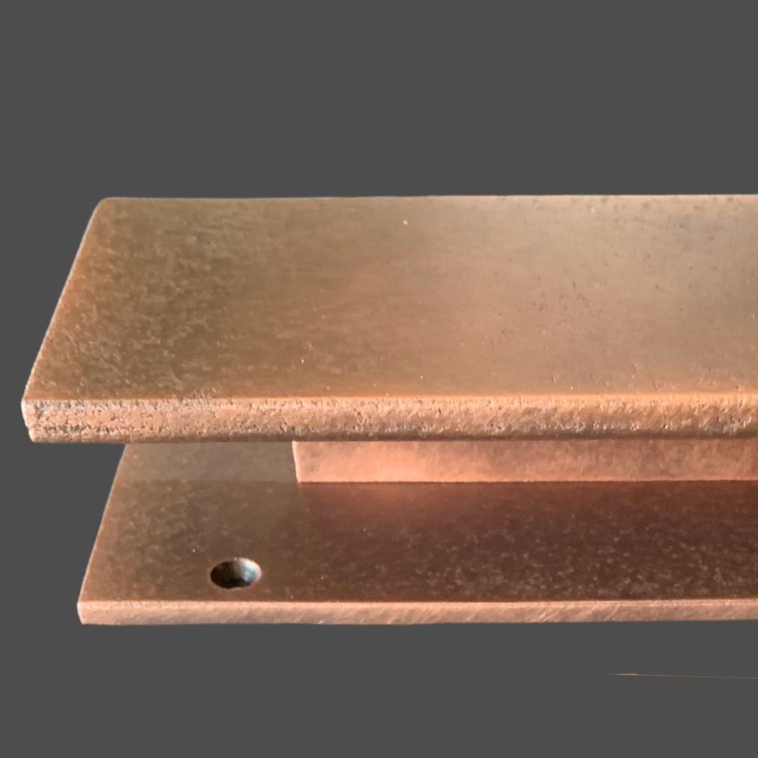 Copper Cast 3 Two rectangular Copper Cast 3 metallic plates with rough edges are stacked with a gap between them. The bottom Copper Cast 3 plate features a small circular hole near one corner and sits on a solid grey background.