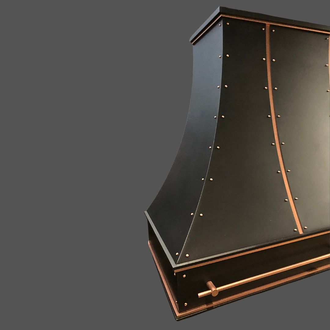 Dark Antique 2 The Dark Antique 2 is a black metal range hood with copper rivets, trim, and towel bar, featuring a curved design and set against a plain gray background.