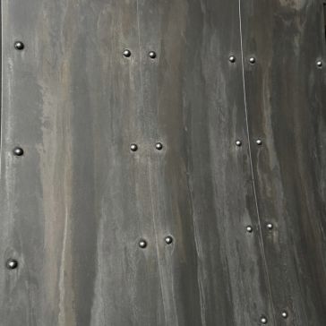 Dark Washed 6258 Close-up of Dark Washed 6258’s metallic surface, showing a wavy texture with rows of small, evenly spaced round rivets. The aged metal has subtle streaks and variations in its gray color.