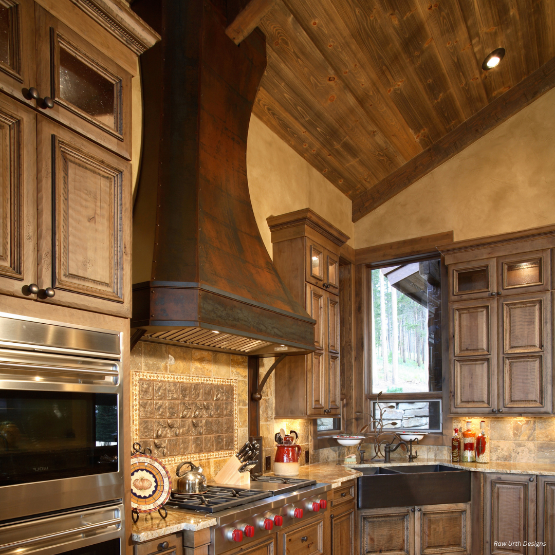 Durango gallery2 The Durango gallery2 features a rustic kitchen with wood cabinets, a large metal range hood, stone backsplash, double wall ovens, gas cooktop, exposed wooden ceiling, and a window letting in natural light to enhance the earthy tones.