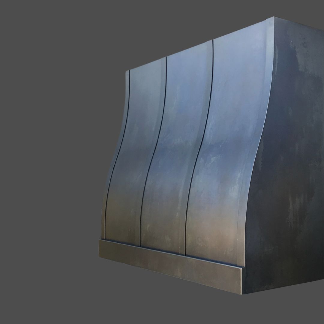 The Gunmetal 3 is a metallic, modern kitchen hood featuring a matte finish and smooth, curved vertical panels, displayed against a solid dark gray background.