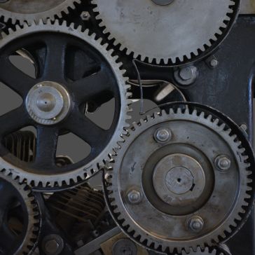 Close-up of Gunmetal 5’s interlocking metal gears, highlighting their teeth and mechanical details against a dark background.