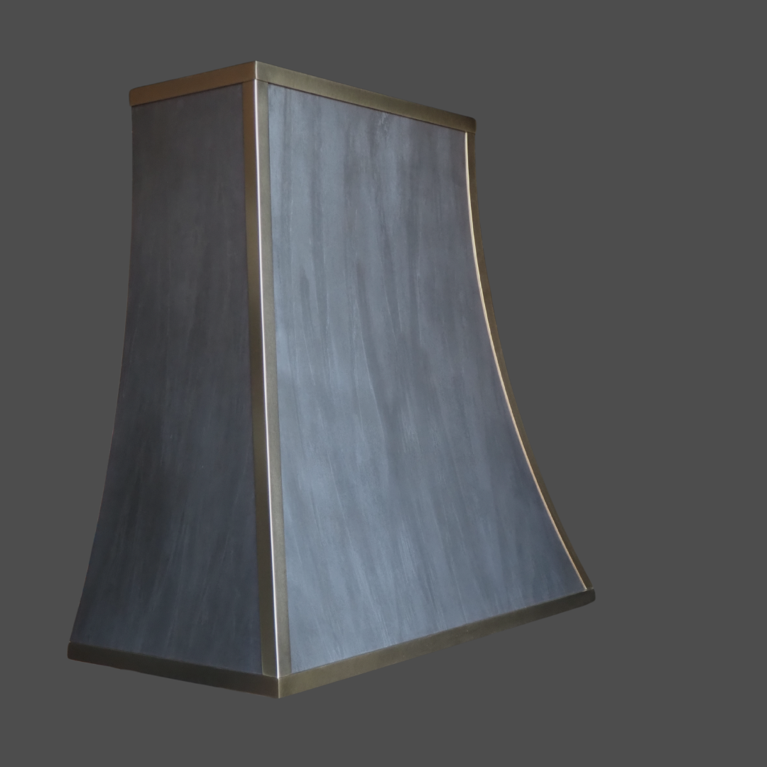 Light Washed 1 The Light Washed 1 is a modern, trapezoidal range hood with a smooth, dark metallic finish and bronze trim, shown against a plain dark gray background.