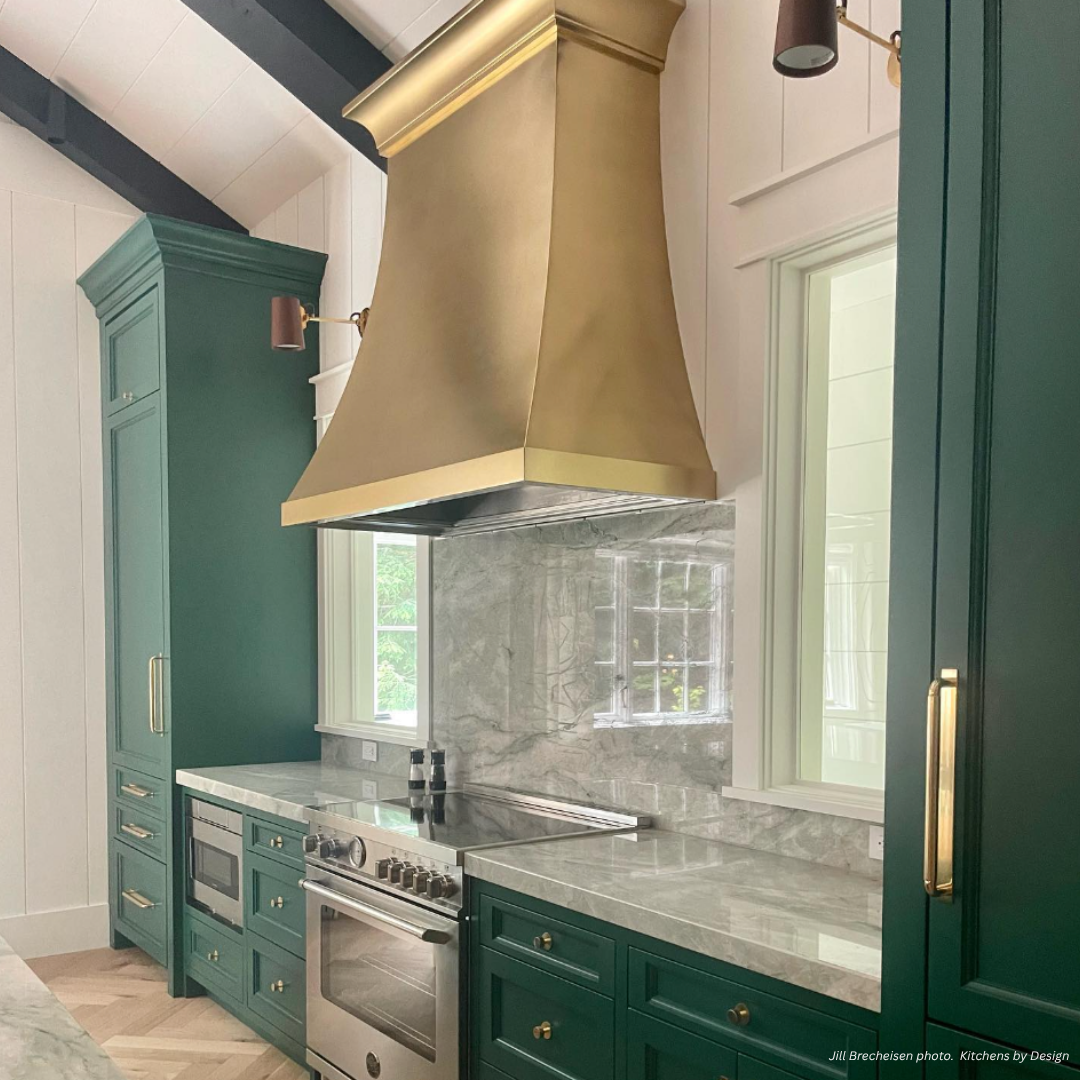 Montrose gallery1 The Montrose gallery1 kitchen showcases green cabinets, marble countertops, a stainless steel stove, and a gold range hood. White-framed windows brighten the modern space, highlighting its elegant design.