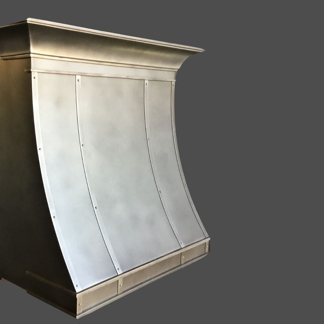 Pewter Antique 2 The Pewter Antique 2 is a large, silver metallic range hood with a curved design and visible rivets, displayed against a plain gray background.