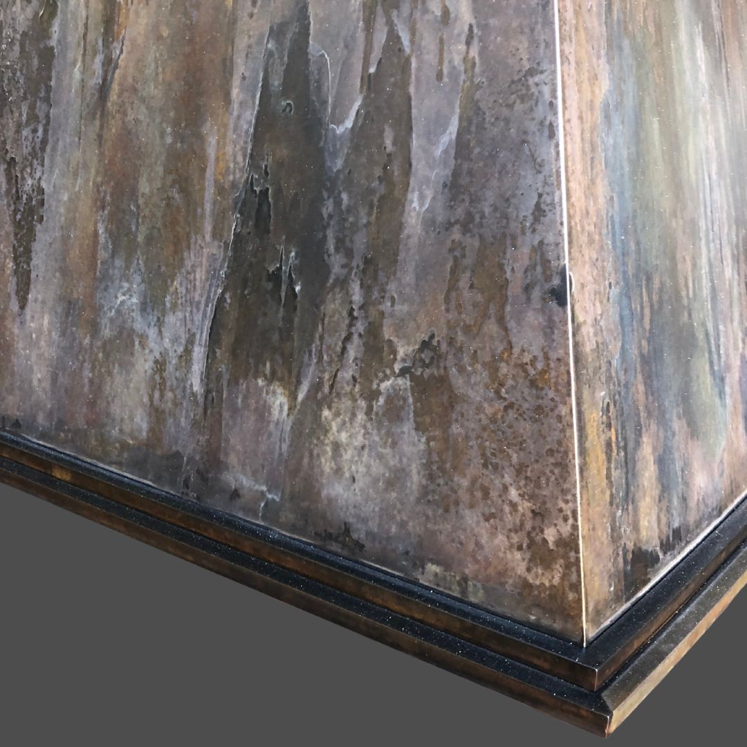 Rustic Reclaimed 3 A close-up of the Rustic Reclaimed 3: a pyramid-shaped, metallic object with a multicolored weathered patina and dark decorative trim at its base.