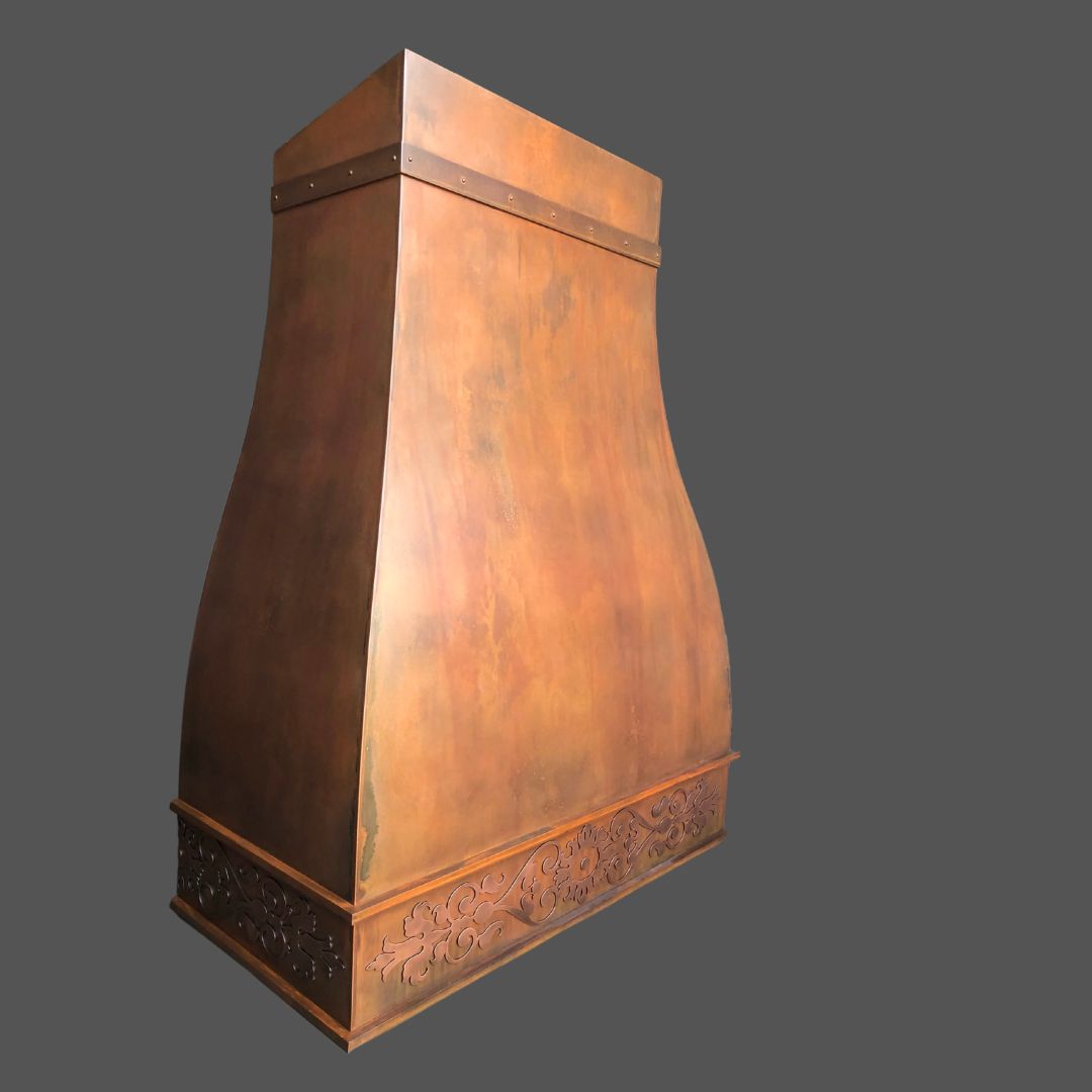 Rusty Rustic Iron 2 The Rusty Rustic Iron 2 is a decorative, bronze-toned metal kitchen range hood with a wide curved base and ornate floral engravings, shown against a plain gray background.
