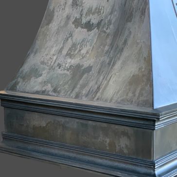 A close-up of Showroom Reclaimed 2, featuring a weathered metallic surface with brushed texture and decorative trim, set against a plain gray background.