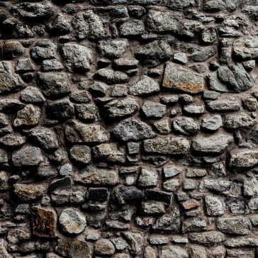 Close-up view of the Showroom Reclaimed 4 wall, featuring variously sized and shaped stones tightly fitted together. Visible gaps highlight the rough textures, with stones ranging in color from gray to brown.