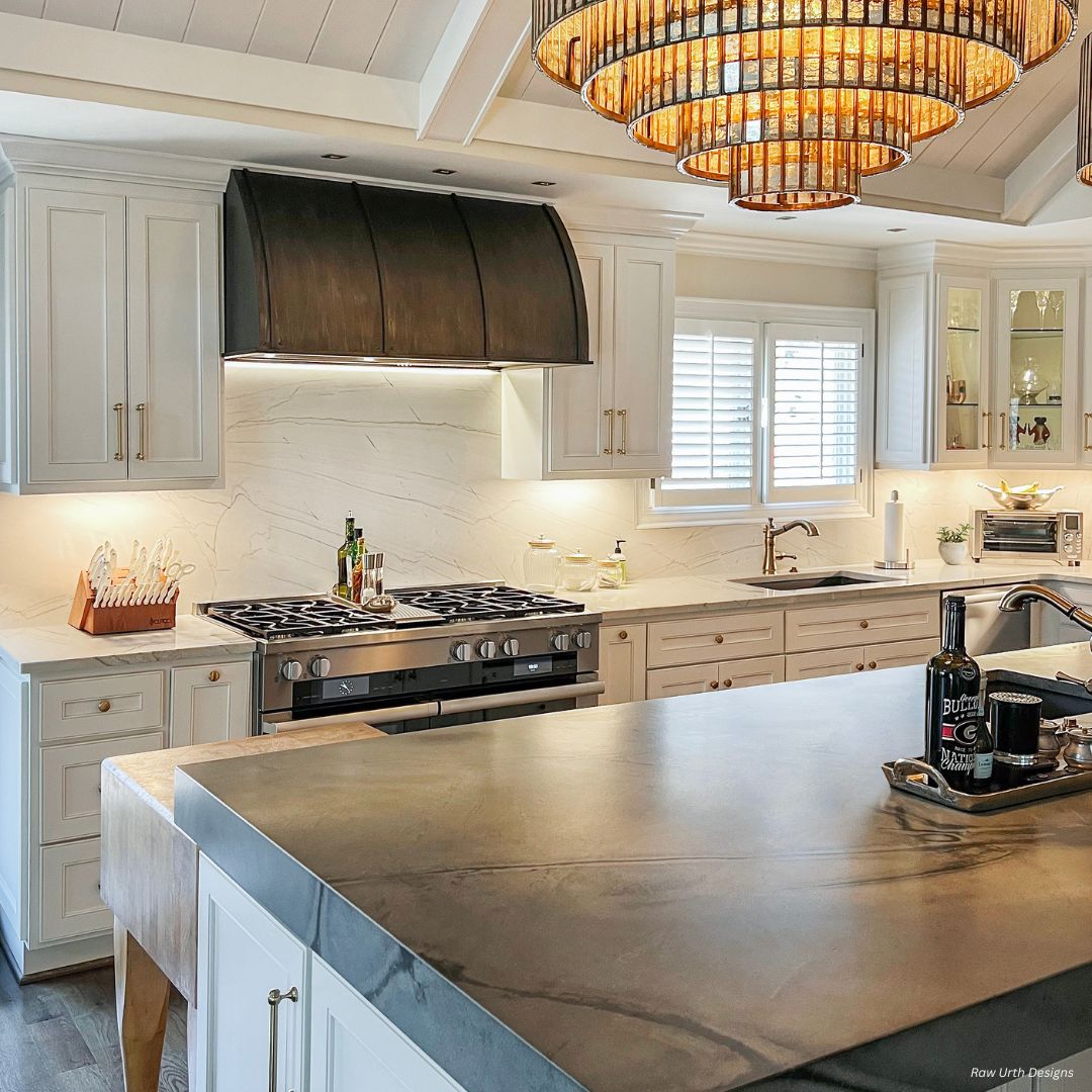 Snowmass gallery 1 Snowmass gallery 1 features a bright, modern kitchen with white cabinets, a spacious gray island, stainless steel stove, marble backsplash, and two large circular gold pendant lights hanging overhead.