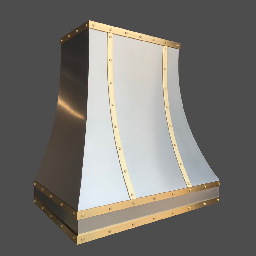 The Stainless Grained 1 is a metallic kitchen range hood with a flared shape, smooth silver panels, and gold-trimmed rivet details, displayed against a plain gray background.
